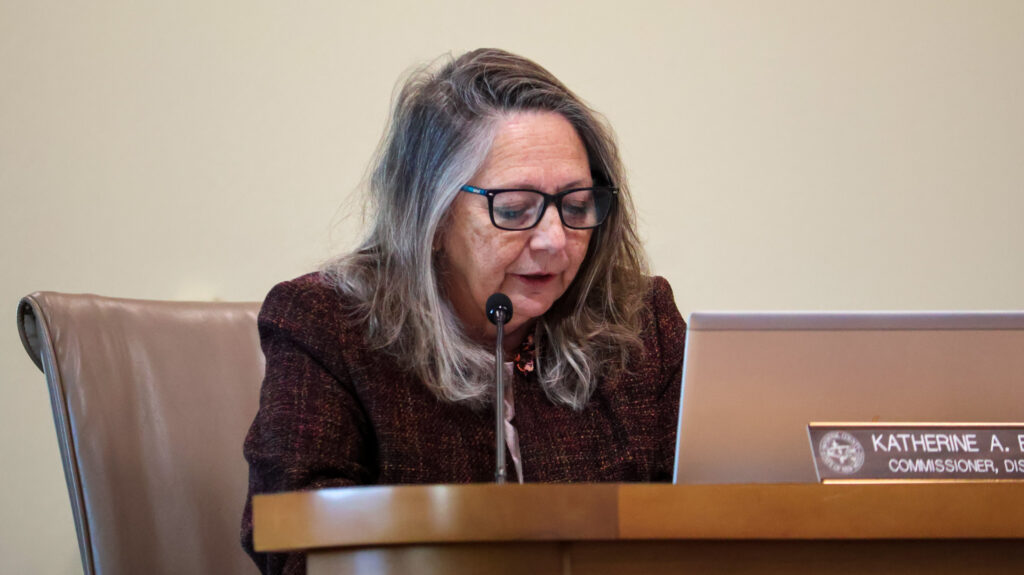 Sandoval County Commissioner Katherine A. Bruch seated behind a desk, speaking into a microphone.