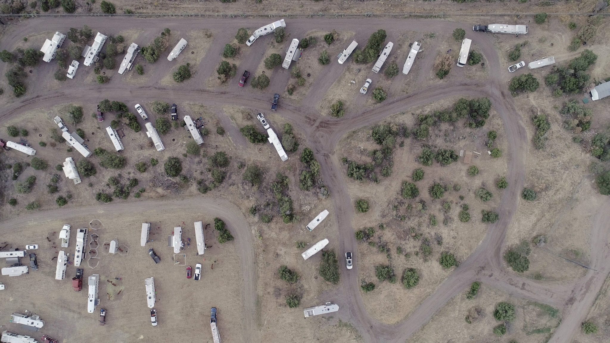Aerial view of the Sandoval County Fairgrounds RV park showing numerous RVs and trailers parked among pinon and juniper trees along dirt access roads