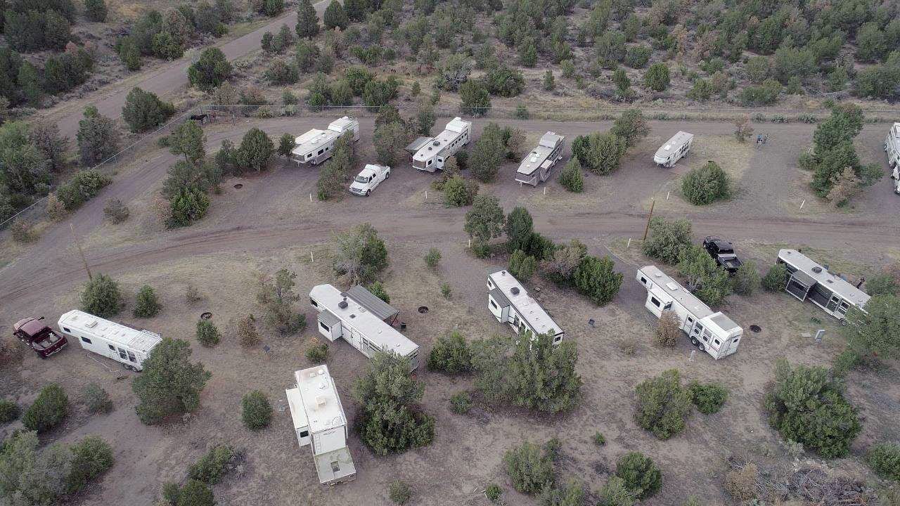 Aerial view of RV and horse trailer sites at the Sandoval County Fairgrounds, with units spaced among trees along a winding dirt road