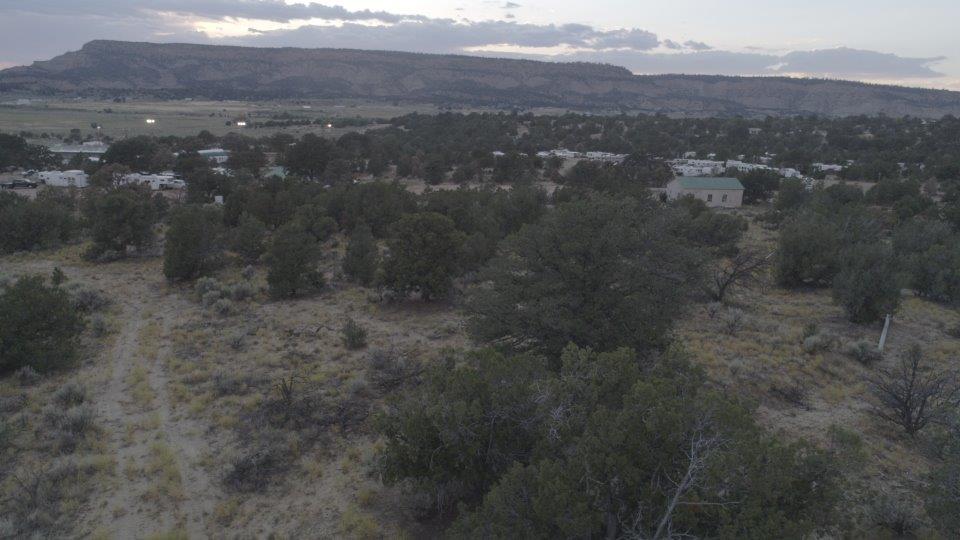 Dusk aerial view looking across the Sandoval County Fairgrounds RV park toward a flat-topped mesa and open high desert valley